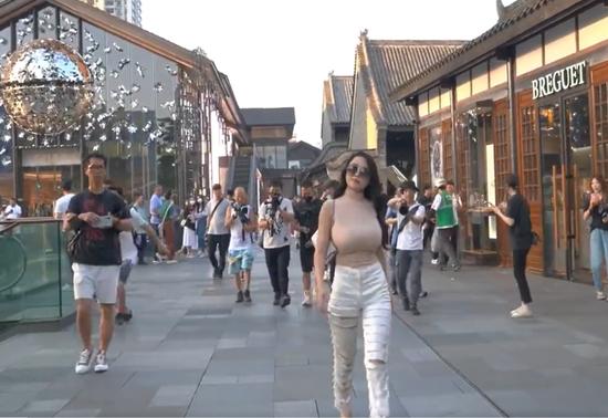 微博视频截图，一名美女走过，身后跟着许多街拍